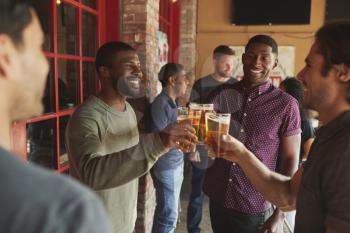 Group Of Male Friends Meeting In Sports Bar Making Toast Together