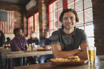 Portrait Of Man In Sports Bar Eating Burger And Fries