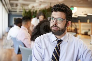 Businessman In Modern Office With Colleagues Meeting Around Table In Background
