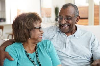 Senior black couple sitting at home, smiling at each other, close up