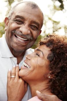 Senior black man and his middled aged daughter embracing and laughing, vertical