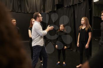 Teacher With Male And Female Drama Students At Performing Arts School In Studio Improvisation Class