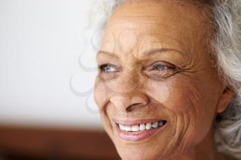 Close Up Of Smiling Senior Woman Sitting On Bed At Home Looking Positive