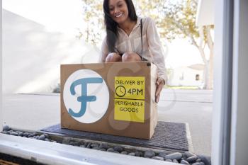 Businesswoman Coming Home To Fresh Food Home Delivery In Cardboard Box Outside Front Door