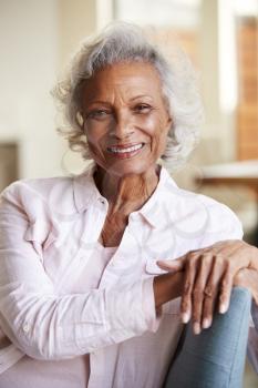Portrait Of Smiling Senior Woman Relaxing On Sofa At Home