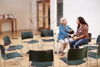 Two Women Talking After Meeting In Community Center