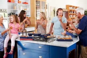 Multi Generation Family Around Kitchen Island Eating Takeaway Pizza Together