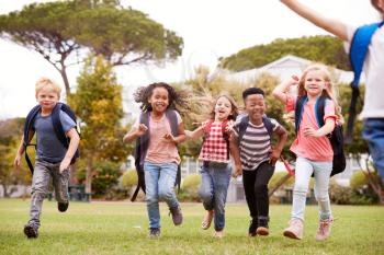 Excited Elementary School Pupils Running Across Field At Break Time