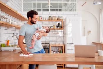 Multi-Tasking Father Holds Sleeping Baby Son And Cleans In Kitchen