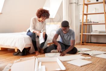 Couple In New Home Putting Together Self Assembly Furniture