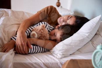 Mid adult woman sleeping in bed with her four year old son, waist up, close up