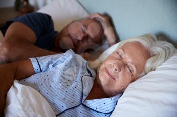Senior white couple lying asleep in their bed, waist up, close up