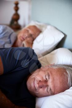 Senior white couple asleep in their bed, close up, vertical