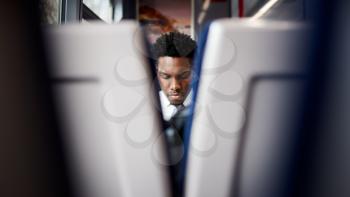 Businessman Sitting In Train Commuting To Work Viewed Between Two Seats