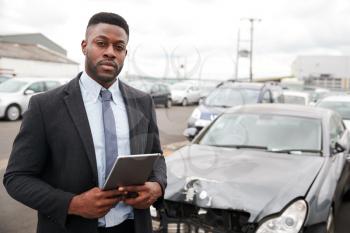 Portrait Of Insurance Loss Adjuster With Digital Tablet Inspecting Damage To Car From Motor Accident