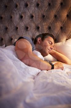 Man Sleeping In Bed Wearing Smart Watch Illuminated By Bedside Lamp