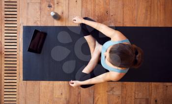 Overhead View Of Woman Sitting On Exercise Mat Using Digital Tablet