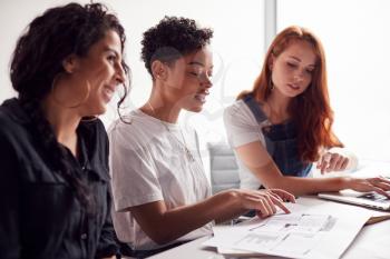 Team Of Young Businesswomen In Meeting Around Table In Modern Workspace