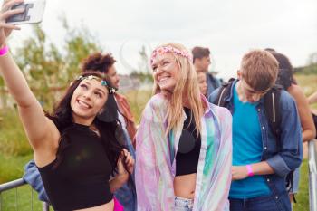 Female Friends Taking Selfie As They Arrive At Entrance To Music Festival
