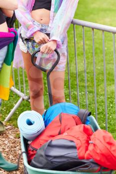 Close Up Of Woman Pulling Trolley Filled With Camping Equipment Arriving At Music Festival Site