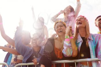 Cheering Young Friends In Audience Behind Barrier At Outdoor Festival Enjoying Music