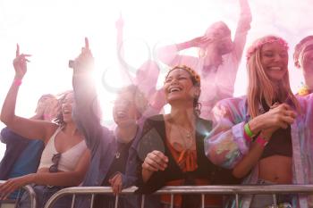 Audience With Colored Smoke Behind Barrier Dancing And Singing At Outdoor Festival Enjoying Music