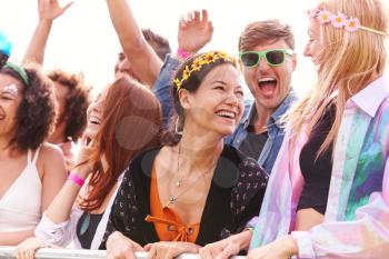 Cheering Young Friends In Audience Behind Barrier At Outdoor Festival Enjoying Music