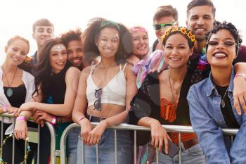 Portrait Of Young Friends In Audience Behind Barrier At Outdoor Music Festival