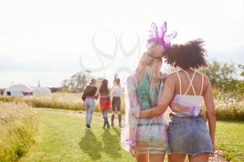 Rear View Of Female Friends Walking Back To Tent After Outdoor Music Festival