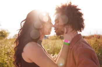 Head And Shoulders Close Up Of Young Romantic Couple Hugging In Countryside Field With Setting Sun