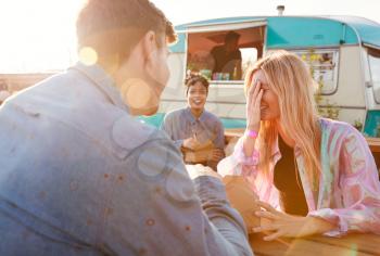 Group Of Friends Eating Takeaway Food From Truck At  Outdoor Music Festival
