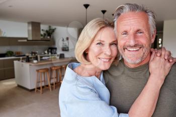 Portrait Of Smiling Senior Couple Standing At Home In Kitchen Together