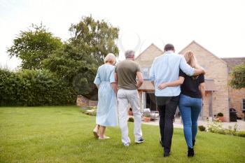 Rear View Of Family With Senior Parents And Adult Offspring Walking And Talking In Garden Together