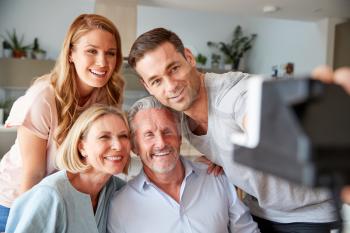 Senior Parents With Adult Offspring Posing For Selfie On Vintage Instant Film Camera