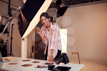 Portrait Of Female Photographer Editing Images From Photo Shoot In Studio