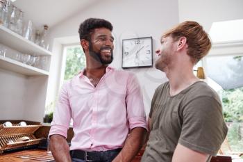 Loving Male Gay Couple Talking At Home In Kitchen Together