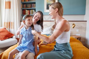 Same Sex Female Couple At Home Getting Daughter Ready For School Plaiting Her Hair