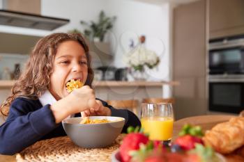 Girl Wearing Uniform In Kitchen Eating Breakfast Cereal Before Going To School