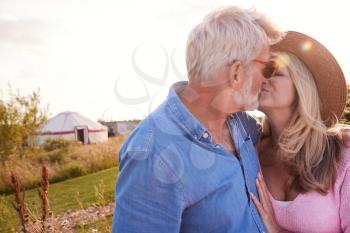 Loving Mature Couple In Countryside Kissing Against Flaring Sun