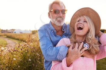 Loving Mature Couple In Countryside Hugging Against Flaring Sun