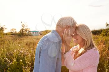 Loving Mature Couple In Countryside Head To Head Against Flaring Sun