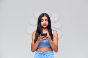 Studio Shot Of Causally Dressed Young Woman Using Mobile Phone