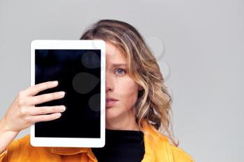 Studio Portrait Of Worried Young Woman Covering Face With Digital Tablet