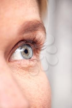 Extreme Close Up Of Eye Of Woman Against White Studio Background