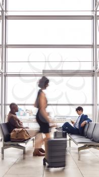 Business Passengers Sitting In Busy Airport Departure Lounge Using Mobile Phones