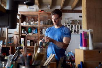 Man In Workshop Choosing Paintbrush For Upcycling And  Craft Projects