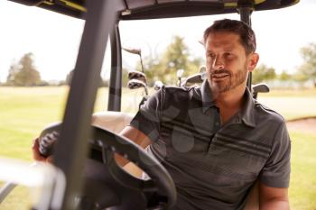 Mature Man Playing Golf Driving Buggy Along Course To Green On Red Letter Day