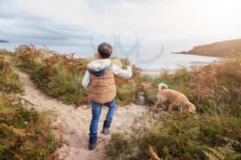 Boy Carrying Fishing Net Exploring Sand Dunes With Pet Dog