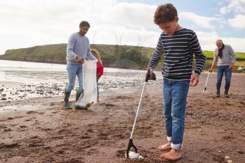 Multi-Generation Family Collecting Litter On Winter Beach Clean Up