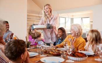 Mother Serving Food As Multi-Generation Family Meet For Meal At Home